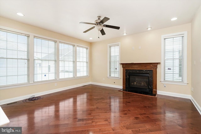 unfurnished living room featuring dark wood-type flooring, ceiling fan, and a high end fireplace