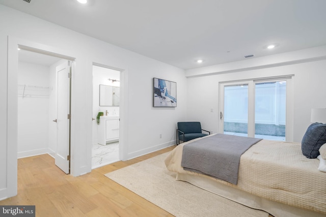 bedroom with a spacious closet, access to exterior, light wood-type flooring, a closet, and ensuite bath