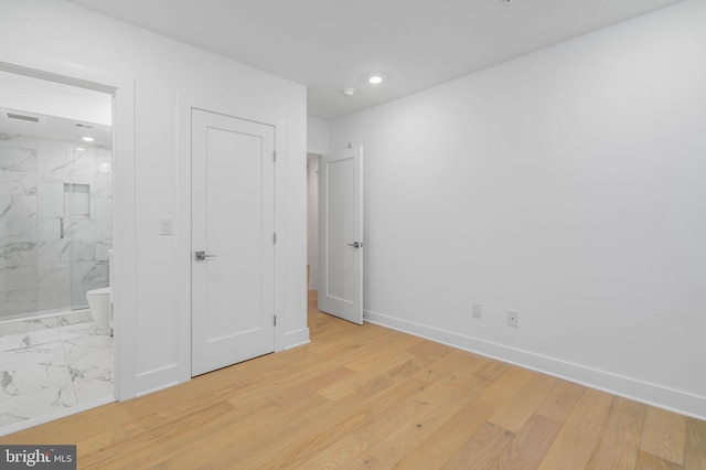 unfurnished bedroom featuring light hardwood / wood-style floors and connected bathroom