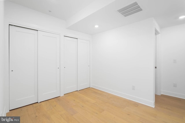 unfurnished bedroom featuring two closets and light hardwood / wood-style flooring