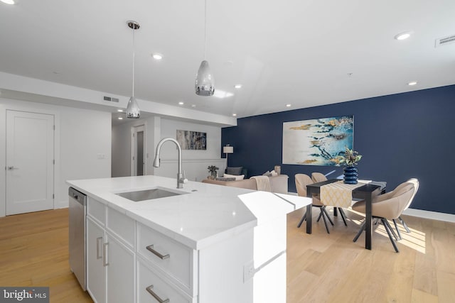 kitchen featuring white cabinets, a kitchen island with sink, pendant lighting, sink, and stainless steel dishwasher