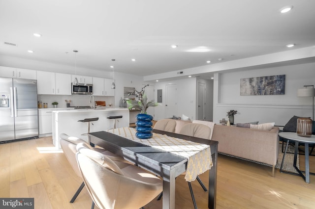 dining room with electric panel, light hardwood / wood-style floors, and sink