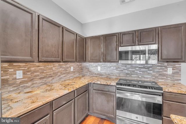 kitchen featuring tasteful backsplash, dark brown cabinetry, light stone countertops, and appliances with stainless steel finishes