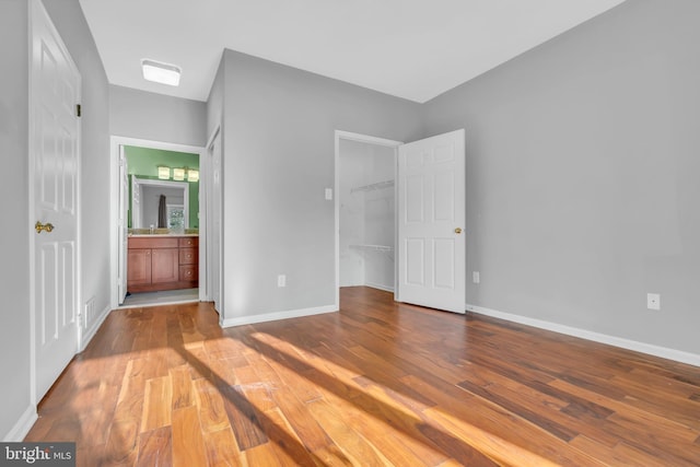 unfurnished bedroom featuring light hardwood / wood-style floors, connected bathroom, and a walk in closet