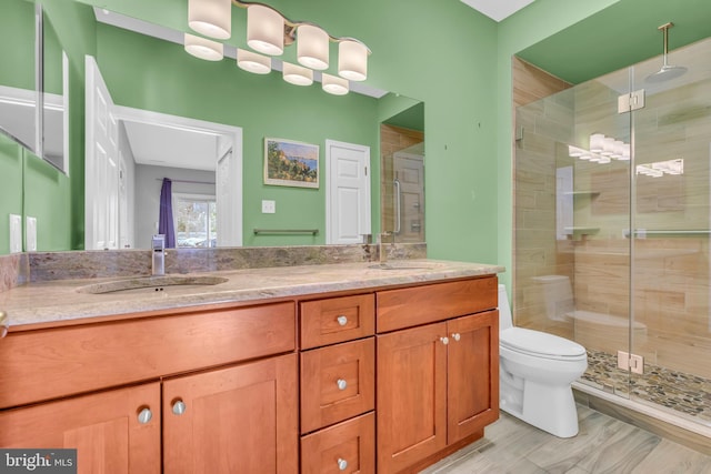 bathroom with vanity, toilet, and a shower with door