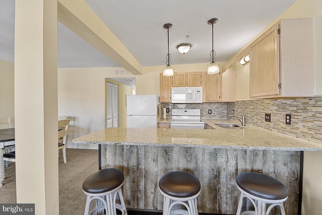 kitchen featuring sink, white appliances, a breakfast bar, kitchen peninsula, and light brown cabinets