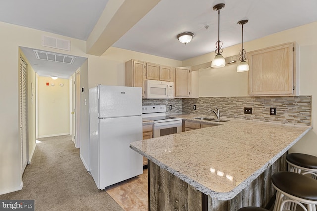 kitchen with sink, white appliances, light brown cabinetry, and kitchen peninsula