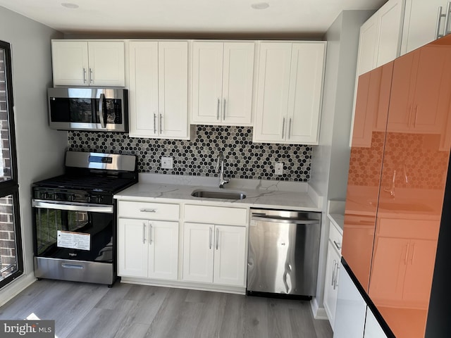 kitchen featuring light stone countertops, appliances with stainless steel finishes, white cabinetry, and sink