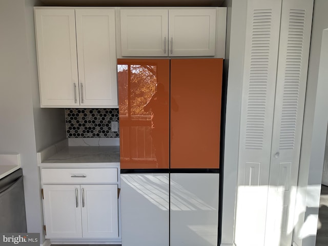 kitchen with white cabinets, refrigerator, and decorative backsplash