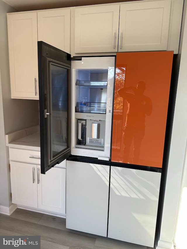 kitchen featuring fridge, light hardwood / wood-style floors, and white cabinetry