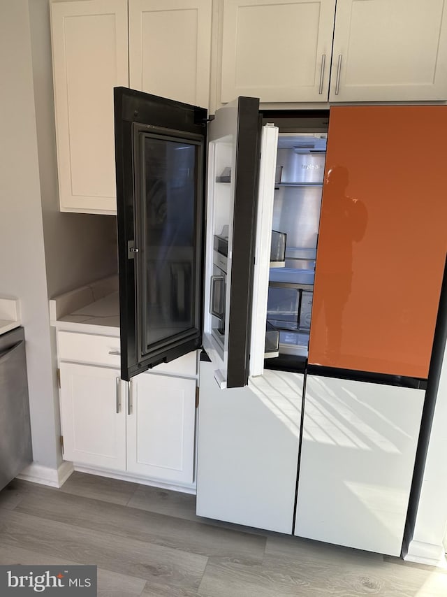 kitchen with fridge, white cabinets, and light hardwood / wood-style floors