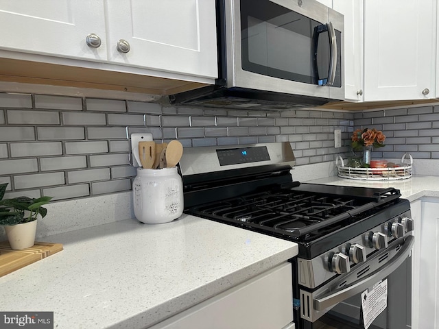 kitchen with stainless steel appliances, white cabinets, decorative backsplash, and light stone countertops