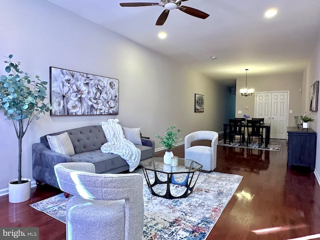 living room with ceiling fan with notable chandelier and dark hardwood / wood-style floors