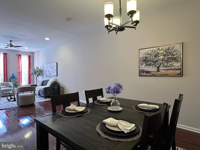 dining room with dark hardwood / wood-style flooring and ceiling fan with notable chandelier