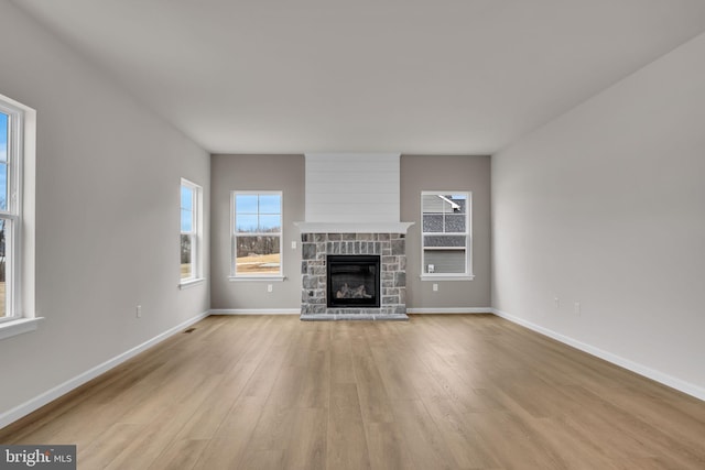 unfurnished living room with light wood finished floors, a fireplace, and baseboards