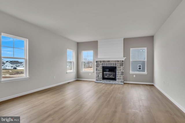 unfurnished living room featuring a fireplace, baseboards, and wood finished floors