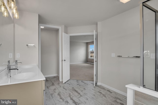 bathroom featuring double vanity, marble finish floor, baseboards, and a sink