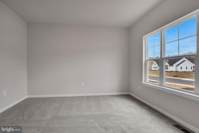 empty room with carpet, visible vents, and baseboards