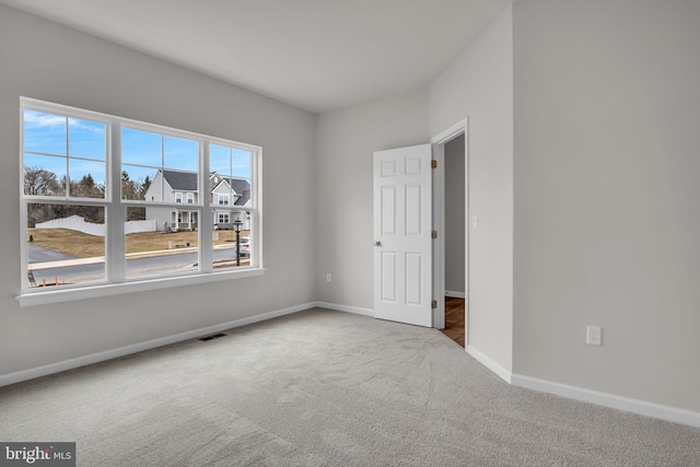 spare room with baseboards, visible vents, and carpet floors