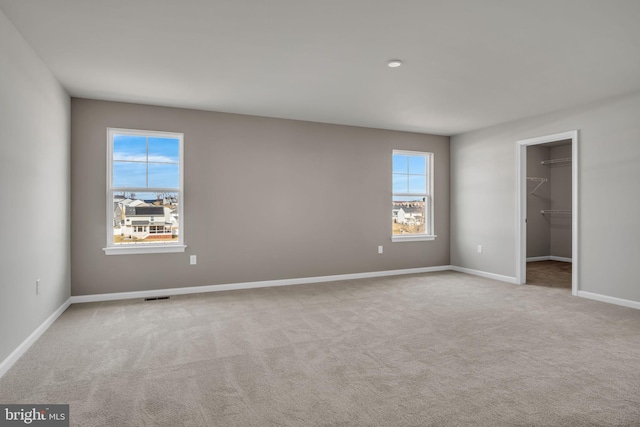 spare room featuring carpet flooring, baseboards, and visible vents