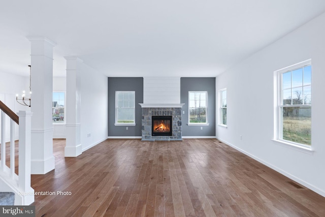 unfurnished living room featuring visible vents, dark wood-type flooring, baseboards, stairs, and ornate columns