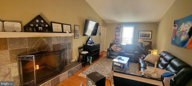 living room with a fireplace, vaulted ceiling, and hardwood / wood-style floors