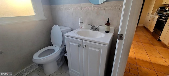 bathroom with toilet, vanity, and tile patterned floors