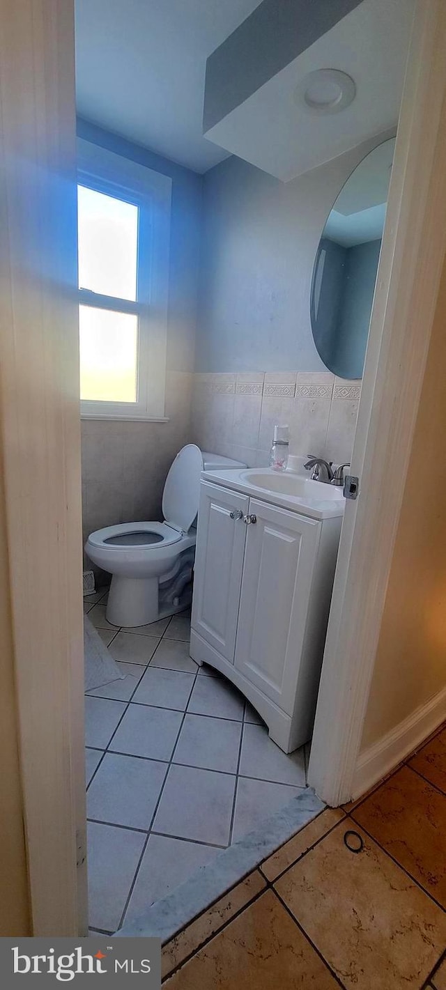 bathroom with toilet, tile patterned flooring, vanity, and tile walls