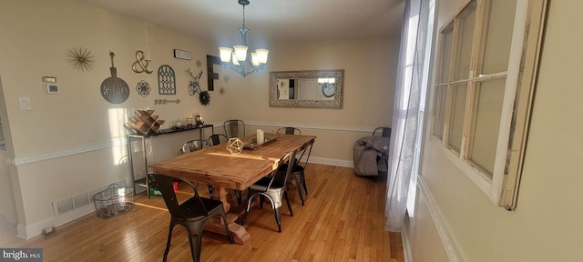 dining area with an inviting chandelier and light hardwood / wood-style floors