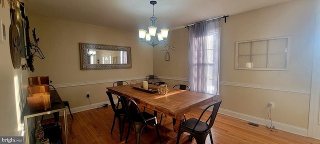 dining area with light hardwood / wood-style flooring and an inviting chandelier