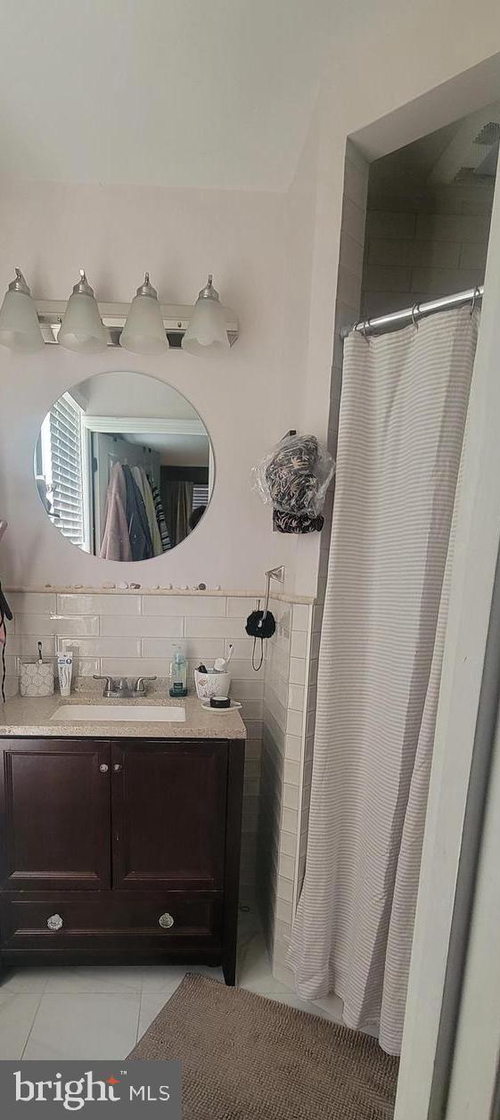 bathroom with tile patterned flooring, walk in shower, and vanity