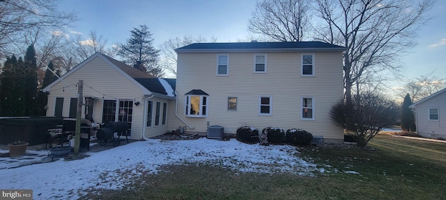 snow covered house featuring central air condition unit and a hot tub