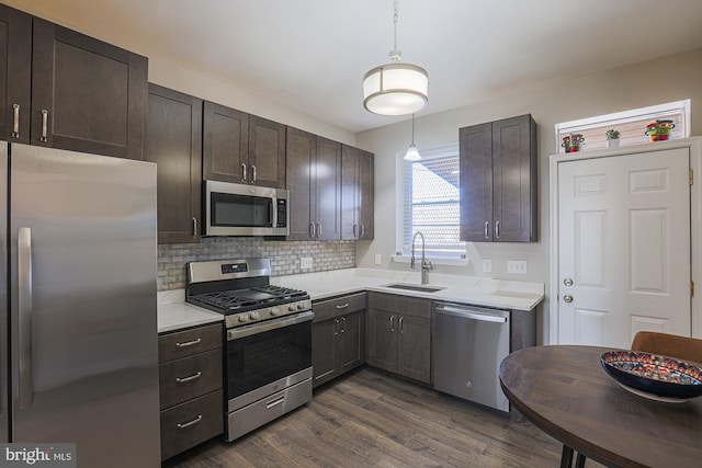 kitchen featuring appliances with stainless steel finishes, dark hardwood / wood-style floors, pendant lighting, sink, and backsplash