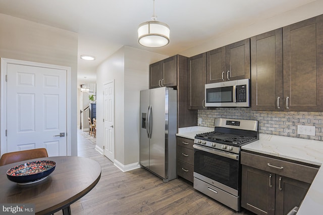 kitchen featuring hardwood / wood-style flooring, stainless steel appliances, light stone counters, and dark brown cabinets