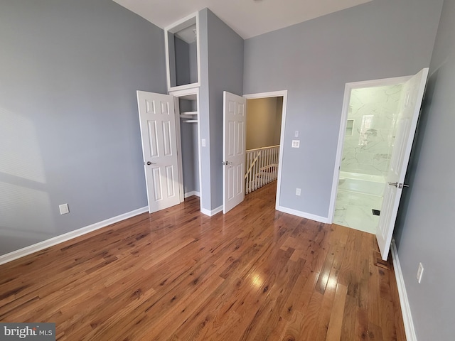 unfurnished bedroom featuring wood-type flooring and ensuite bath