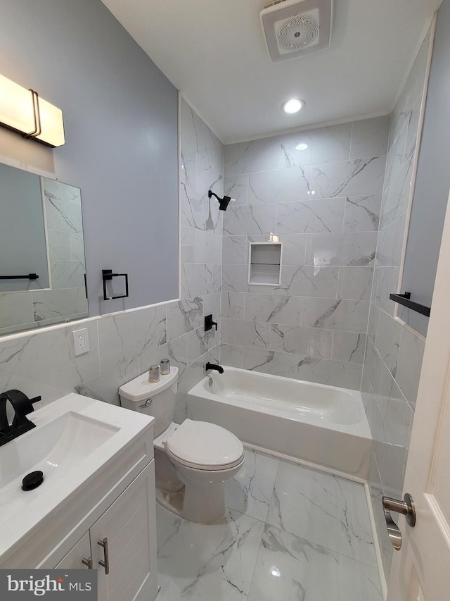 full bathroom featuring toilet, vanity, tile walls, and tiled shower / bath