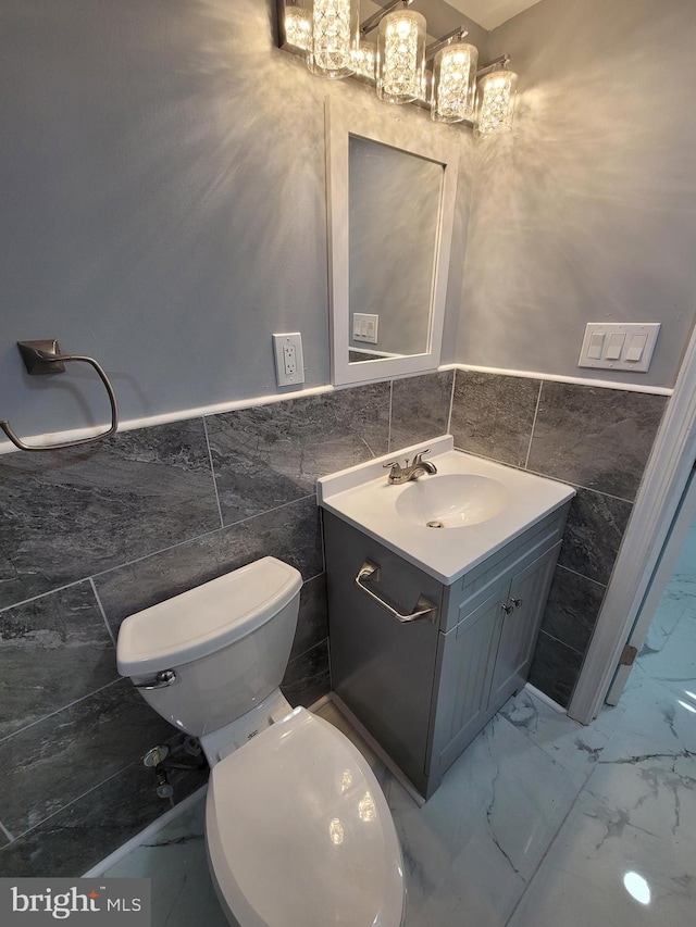 bathroom with tile walls, toilet, and vanity