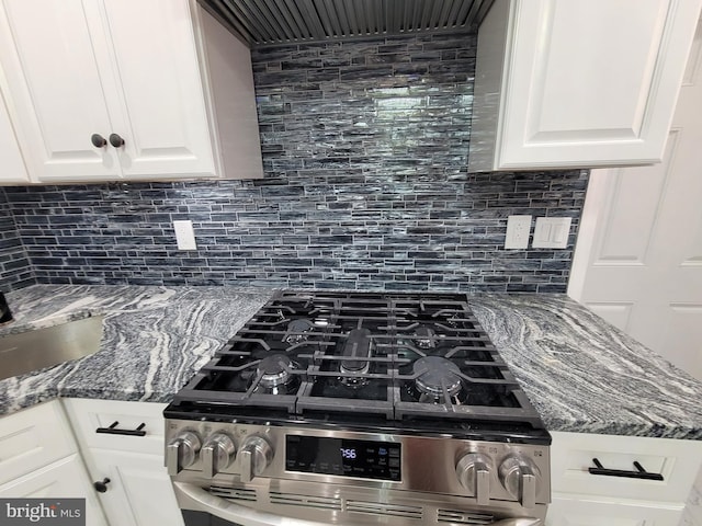 room details with dark stone counters, white cabinets, tasteful backsplash, and stainless steel gas range