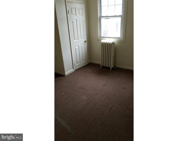 carpeted spare room featuring radiator heating unit