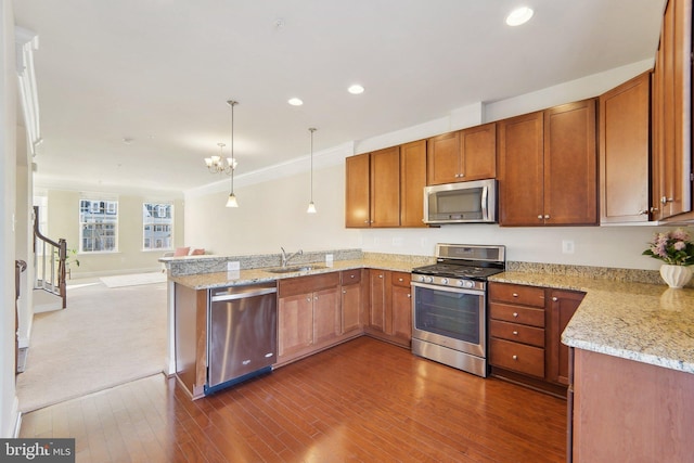 kitchen with kitchen peninsula, dark colored carpet, stainless steel appliances, pendant lighting, and sink