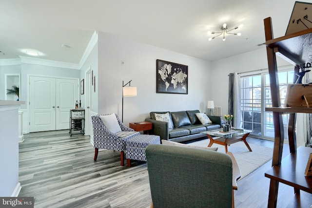 living room featuring an inviting chandelier, light hardwood / wood-style floors, and crown molding