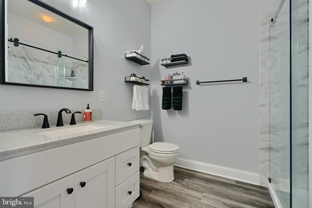 bathroom with toilet, wood-type flooring, vanity, and a shower with shower door