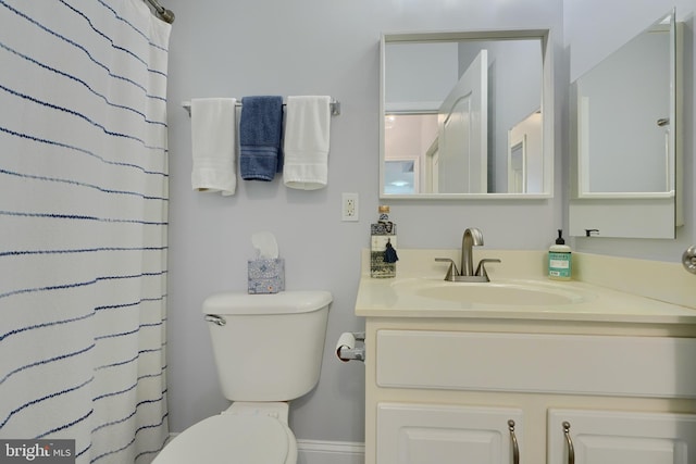 bathroom featuring toilet, curtained shower, and vanity