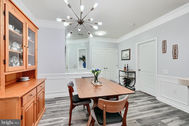 dining area with an inviting chandelier, crown molding, and light hardwood / wood-style flooring