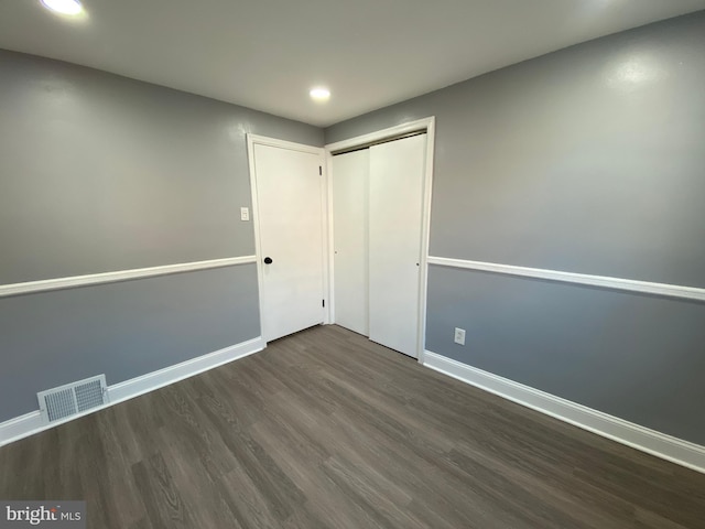 unfurnished bedroom with dark hardwood / wood-style floors and a closet