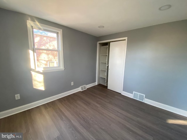 unfurnished bedroom with a closet and dark hardwood / wood-style floors