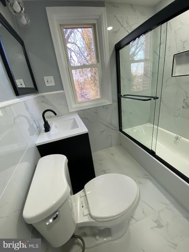 full bathroom with toilet, vanity, tile walls, and bath / shower combo with glass door