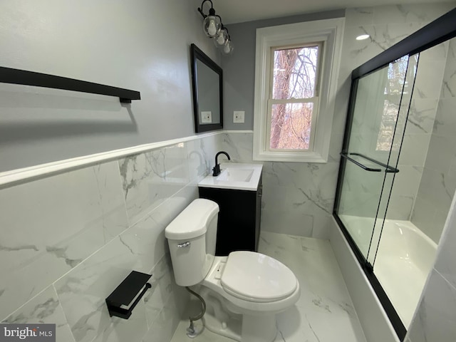 full bathroom featuring tile walls, toilet, vanity, and combined bath / shower with glass door