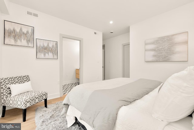 bedroom with light wood-type flooring and ensuite bath