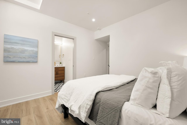 bedroom with ensuite bathroom and light hardwood / wood-style flooring